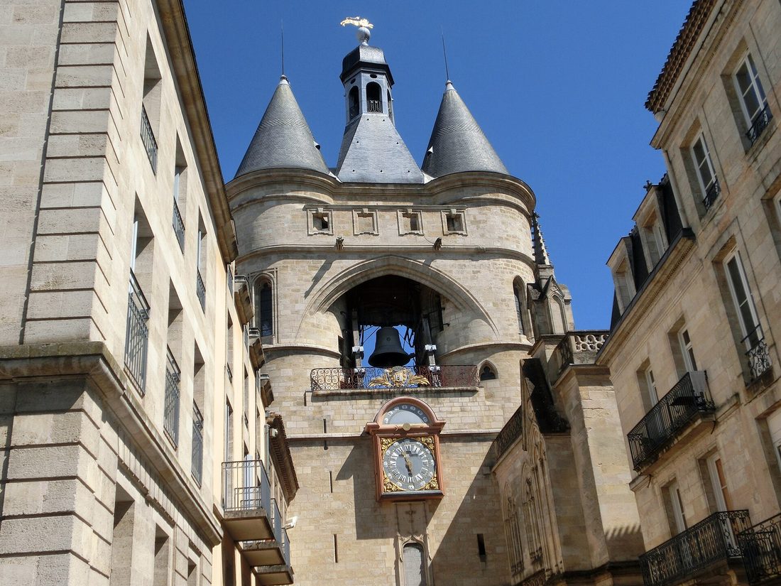 La Grosse Cloche de Bordeaux, avec ses deux tours à toits pointus, sa cloche et son horloge, entre deux immeubles